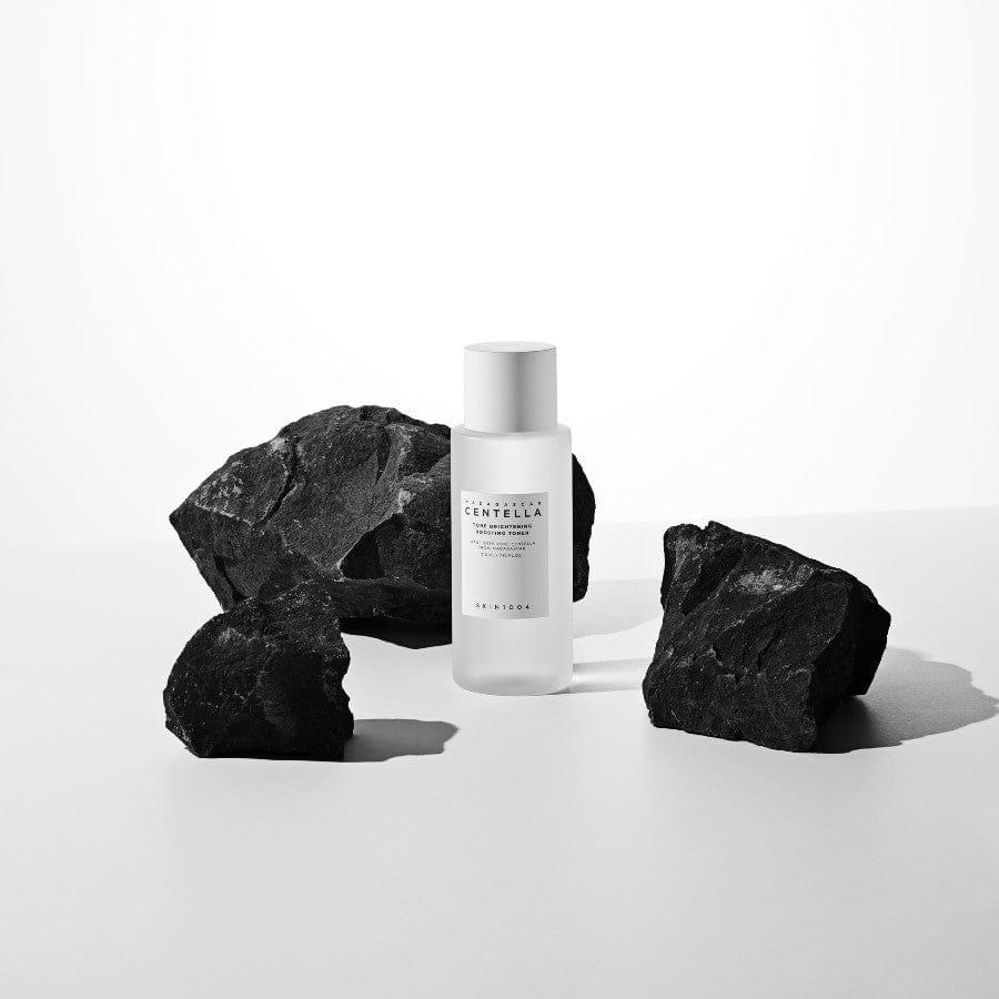 Toner SKIN1004 Madagascar Centella Tone Brightening Boosting Toner posé au milieu de pierres noires